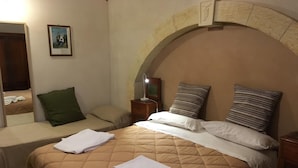 A hotel room with a bed, a nightstand, a lamp, a mirror, and a framed picture on the wall.
