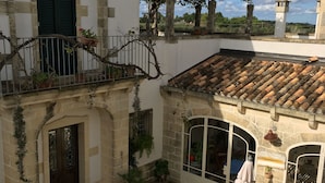A courtyard with a tiled roof, potted plants, a dog, and a sign indicating a restaurant.