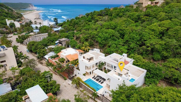 A coastal resort with a pool, multiple buildings, and lush greenery. - Surfside Condo with Private Pool – 3 Minutes to the Beach (Huatulco)