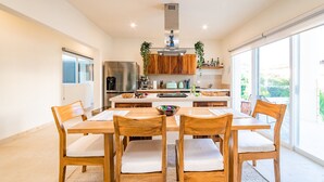 A modern kitchen with wooden cabinets, a stainless steel refrigerator, and a large window. - Surfside Condo with Private Pool – 3 Minutes to the Beach (Huatulco)