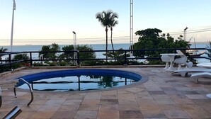 A swimming pool with a tiled deck, surrounded by outdoor furniture and a railing. - Apartamento Luxo em Hotel - Beira Mar Fortaleza (Fortaleza)