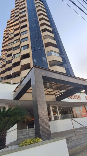 A modern high-rise building with a glass facade and a covered entrance area. - Apartamento Luxo em Hotel - Beira Mar Fortaleza (Fortaleza)