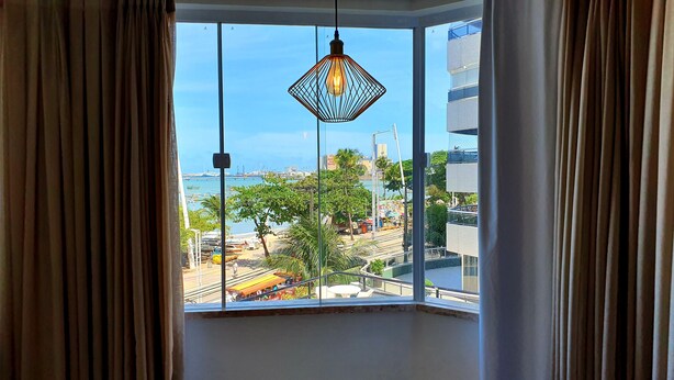 A room with a large window overlooking a marina with boats and buildings. - Apartamento Luxo em Hotel - Beira Mar Fortaleza (Fortaleza)