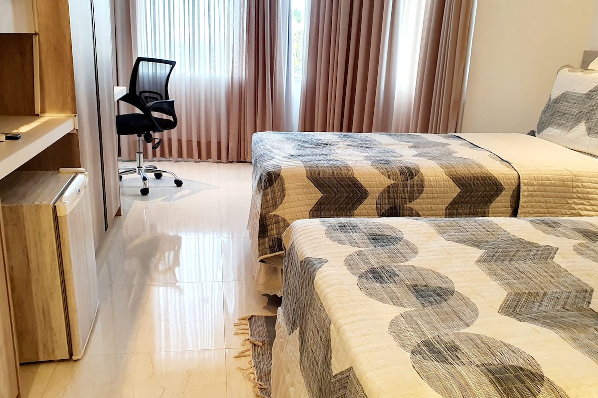 A hotel room with a bed, a desk, and a chair.