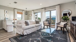 A modern living room with a sofa, chairs, a glass table, and a large window with curtains. - Your Private Inlet Beach Escape Awaits-Top Floor, Gulf Views, Community Pool (Inlet Beach)