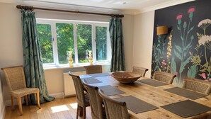 A dining area with a wooden table, wicker chairs, and a large woven bowl. - The Bridge House, Dunbar including hot tub (Dunbar)