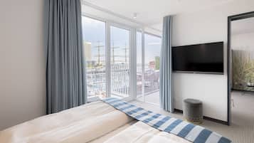 A hotel room with a large bed, a flat-screen TV, and a balcony with a view of the city.