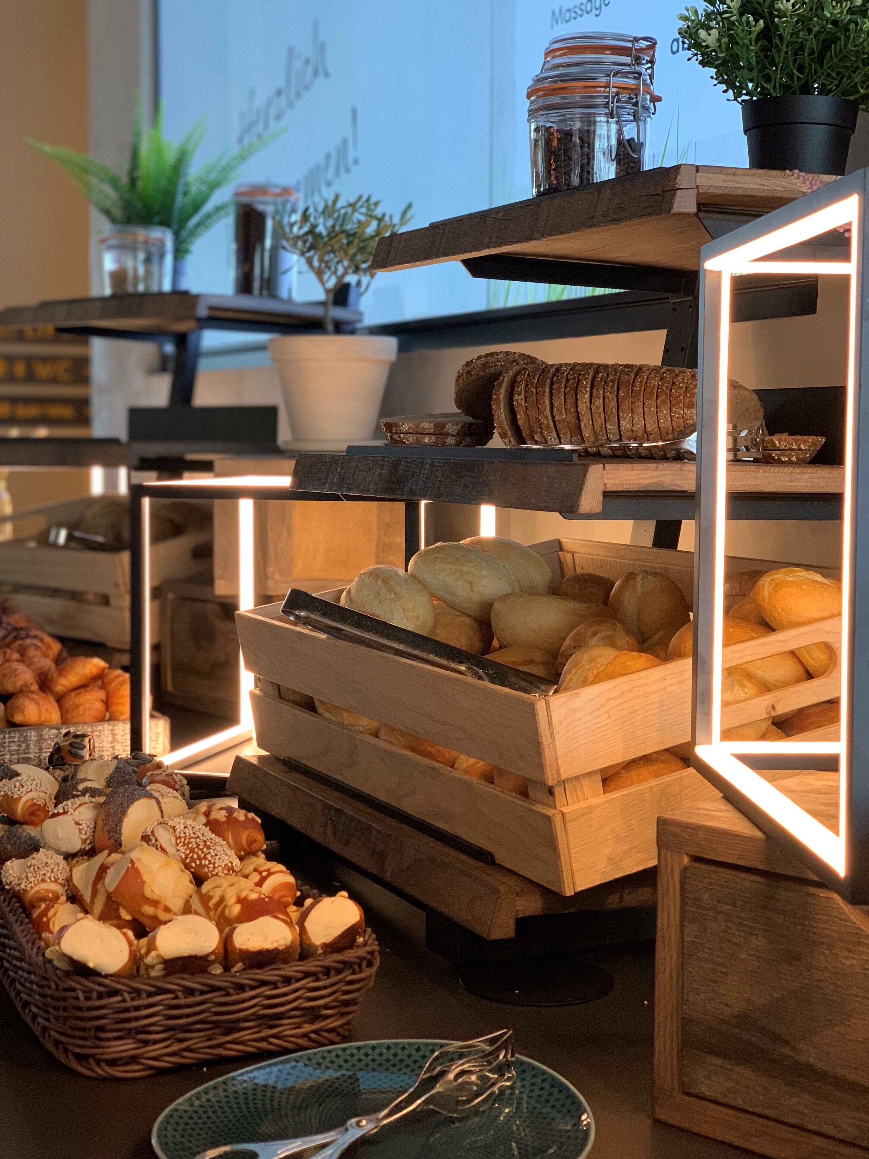 A bakery display with various baked goods, including bread and pastries, arranged on wooden shelves and in baskets.