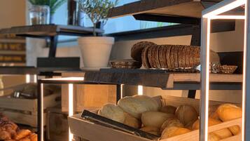 A bakery display with various baked goods, including bread and pastries, arranged on wooden shelves and in baskets.