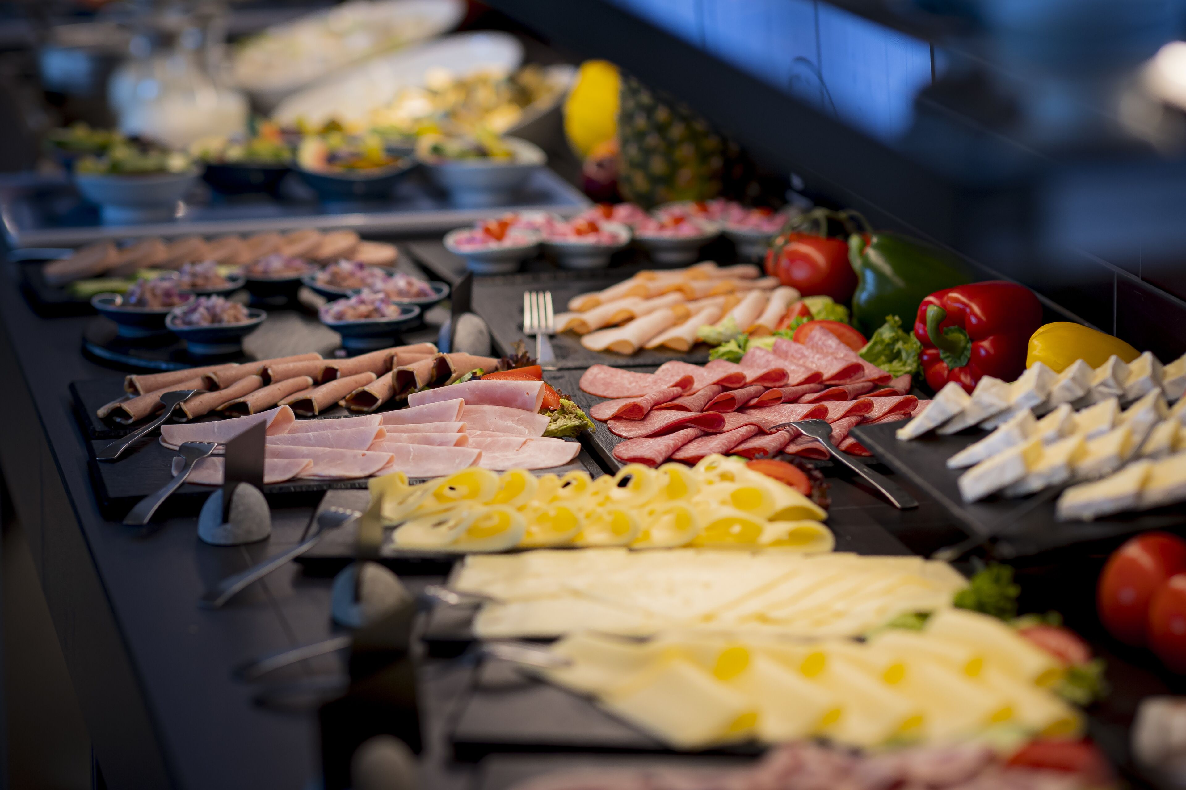 A buffet with various meats, cheeses, and fruits.