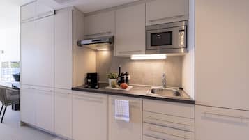 A modern kitchen with white cabinetry, a stainless steel microwave, a built-in oven, and a sink.