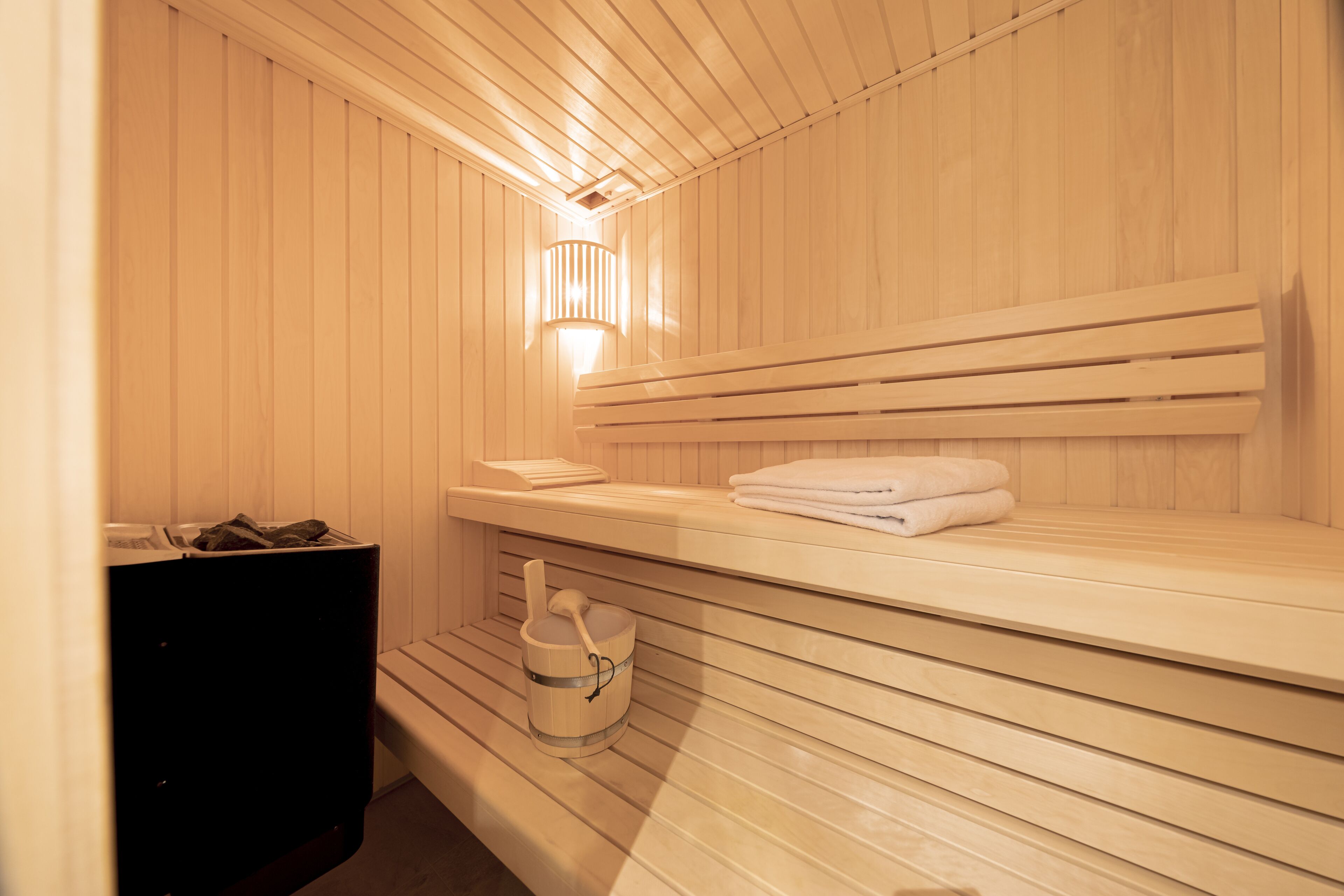 Un sauna avec des bancs en bois, un porte-serviettes et une petite poubelle.