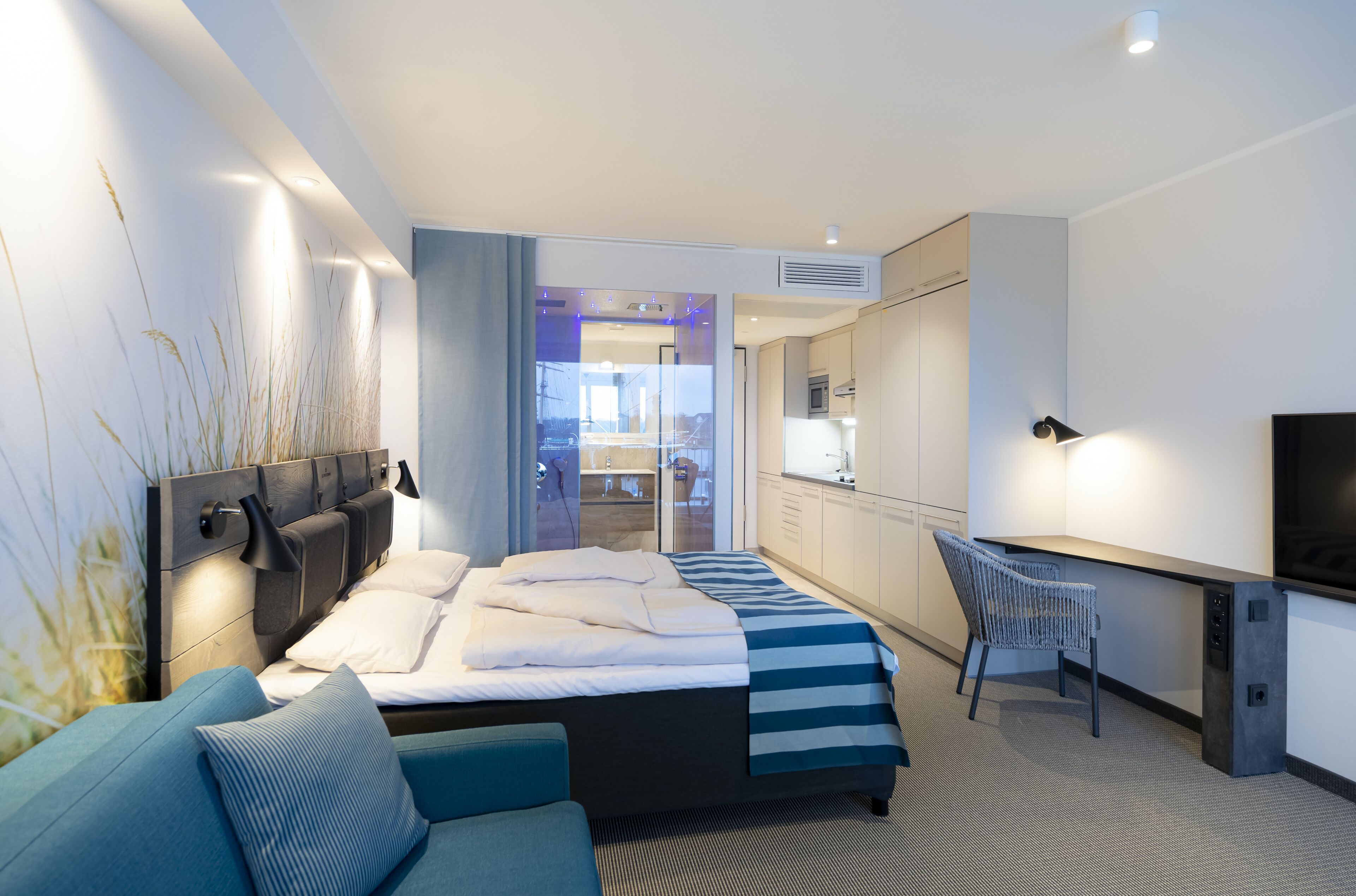 A modern hotel room with a bed, a desk, and a TV.