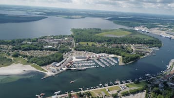 An aerial view of a coastal city with a marina, residential areas, and a large cruise ship docked.