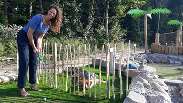 A person playing golf in a park with a wooden fence and rocks.