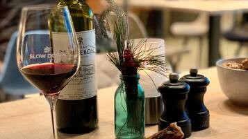 Una mesa de comedor con un pollo asado, patatas y una copa de vino tinto.