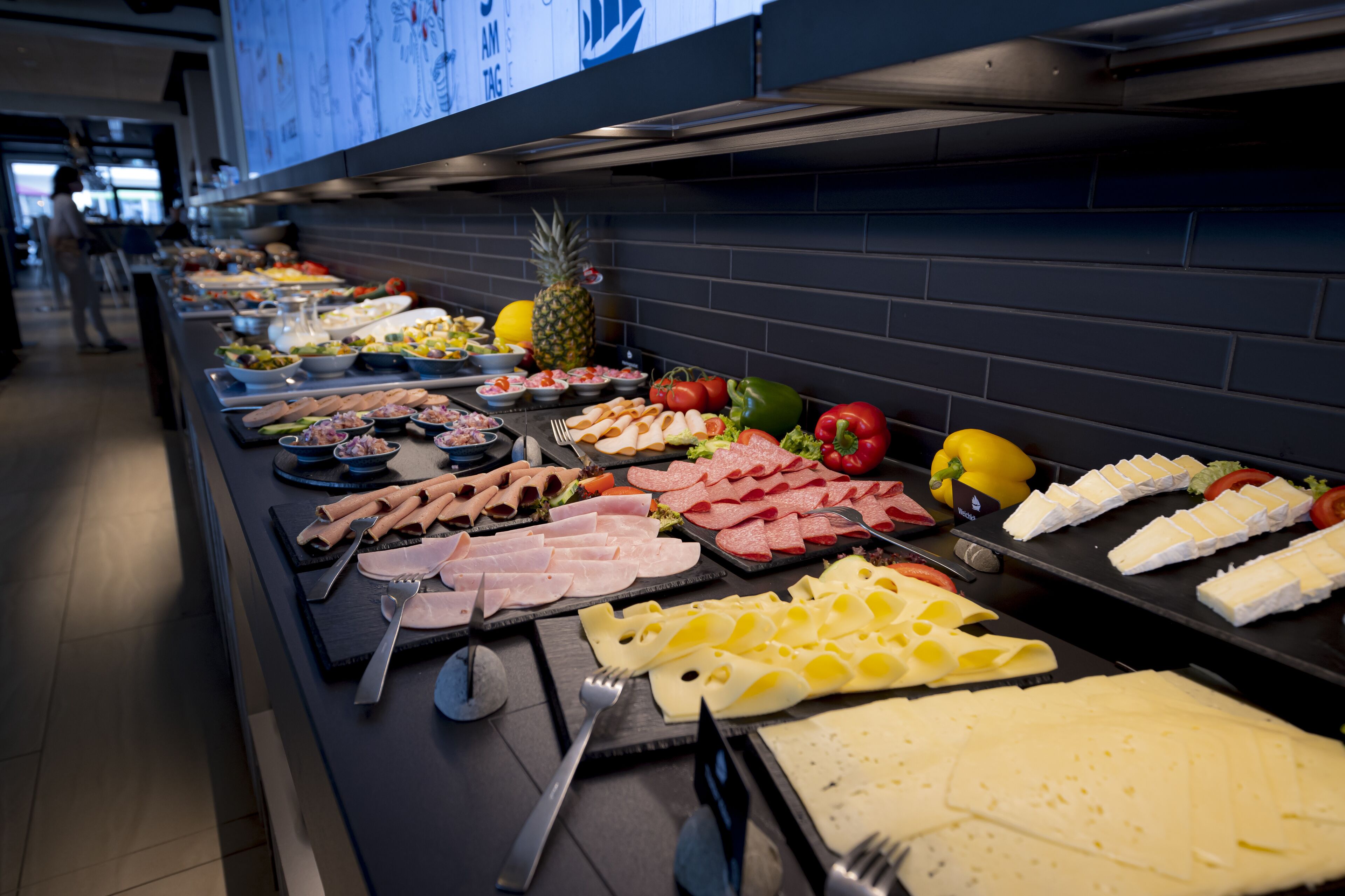 Un buffet proposant une variété de plats, notamment des viandes, des fromages et des fruits.