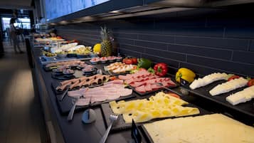 Un buffet proposant une variété de plats, notamment des viandes, des fromages et des fruits.
