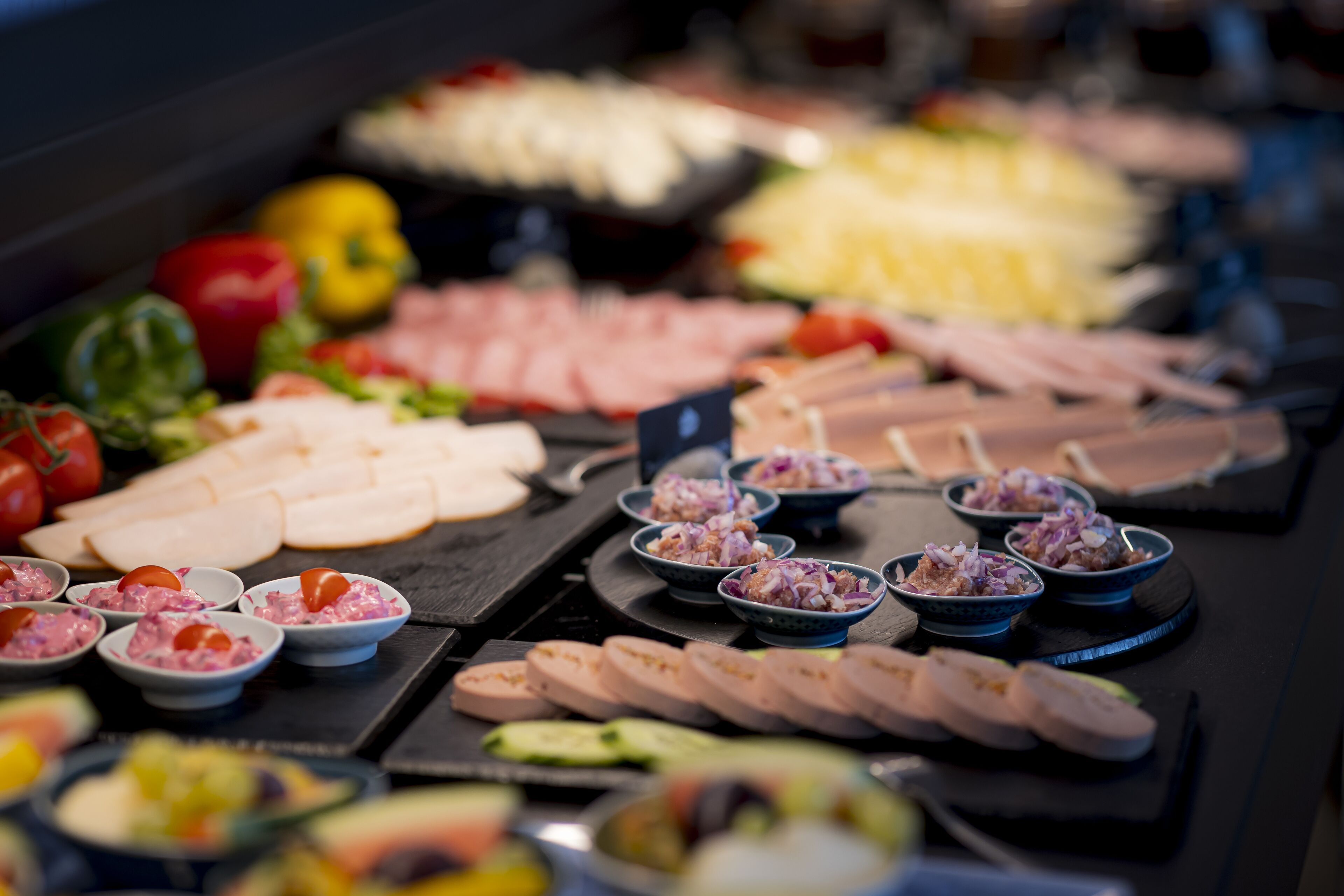 A buffet with various food items including meats, cheeses, and salads.