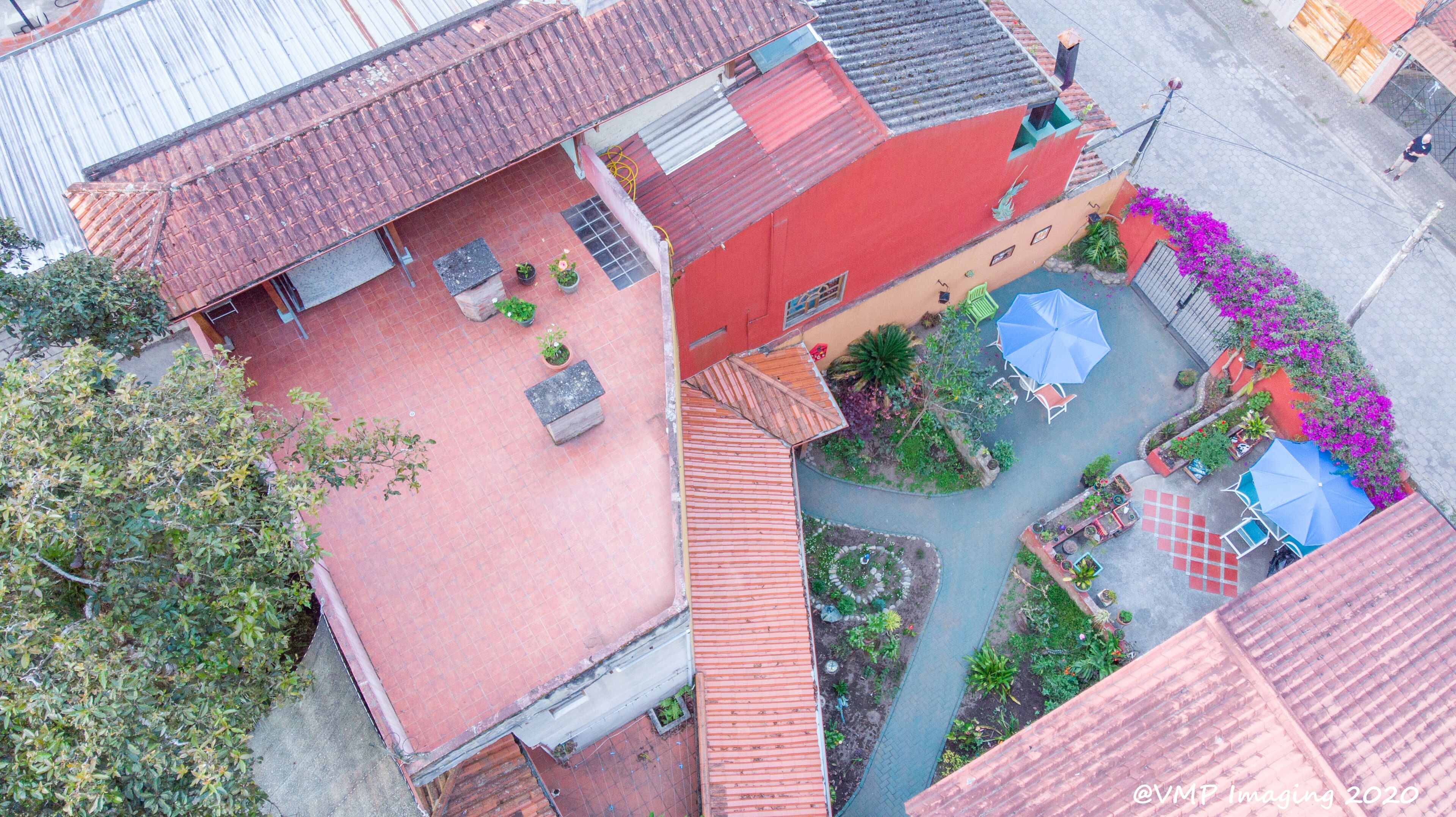 An aerial view of a courtyard with red-tiled roofs, potted plants, and outdoor seating areas.