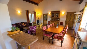 A dining area with a wooden table and chairs, a sofa, and a potted plant. - Villa L'Olivier with Private Pool and Spa in South Ardèche (Joyeuse)