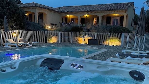 A hot tub with a control panel, surrounded by lounge chairs and a pool area with a house in the background. - Villa L'Olivier with Private Pool and Spa in South Ardèche (Joyeuse)
