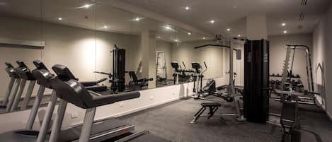 Un gimnasio moderno con cintas de correr, bicicletas estáticas y máquinas de pesas.