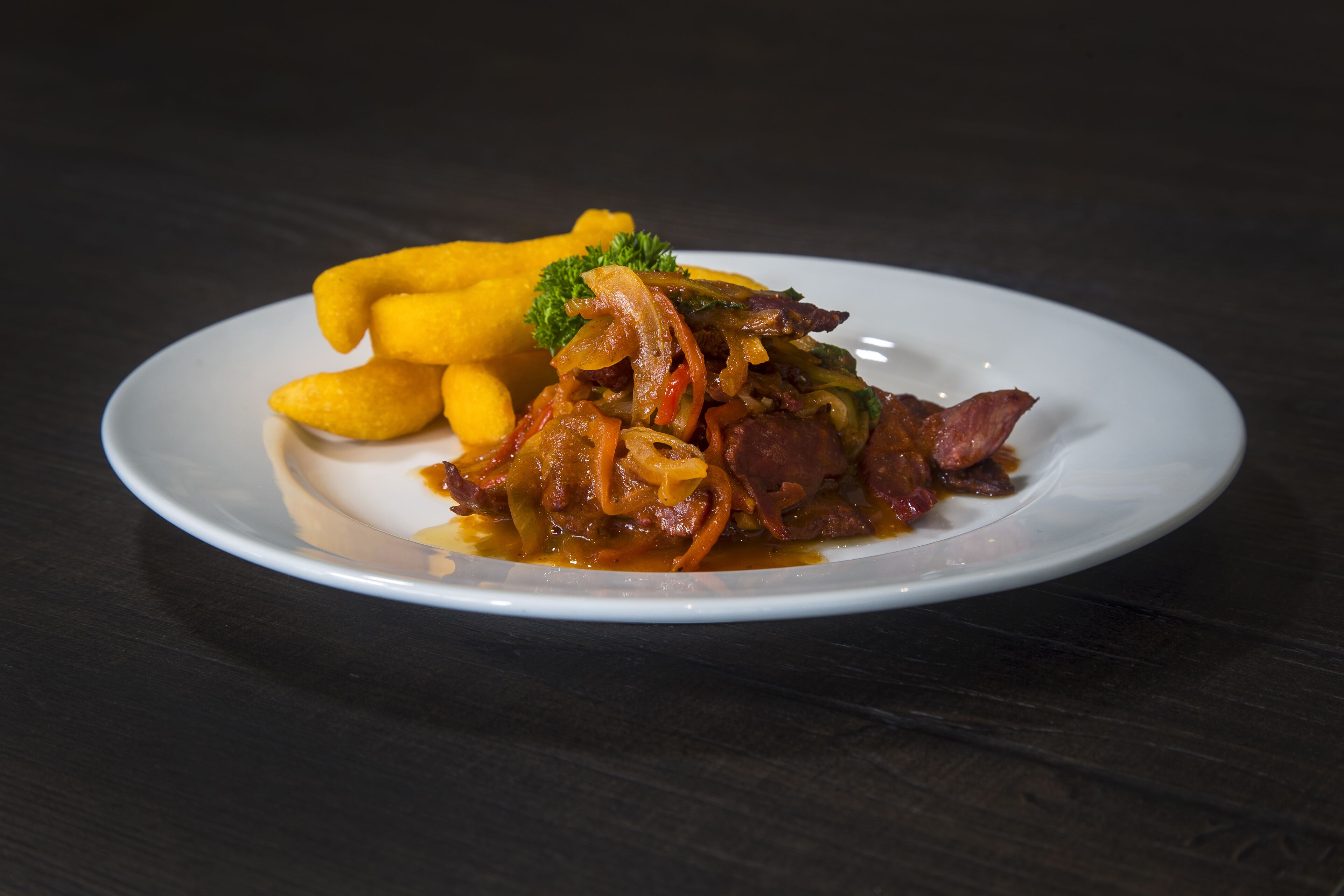 A plate of food with meat, vegetables, and fries on a white plate.