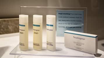 Presentación de productos Neutrogena, incluyendo champú, acondicionador, loción corporal, una pastilla de jabón y un letrero sobre objetos olvidados.