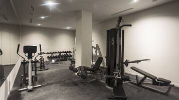 A gym with various exercise equipment, including treadmills, weight machines, and dumbbells.