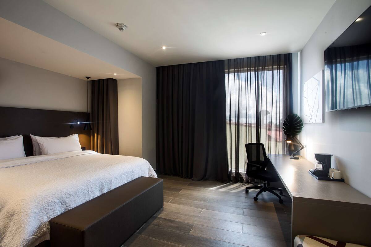 A modern hotel room with a large bed, a desk, and a chair.
