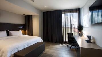 A modern hotel room with a large bed, a desk, and a chair.
