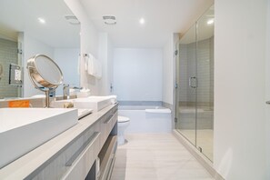 Une salle de bain moderne avec une douche à parois de verre, des toilettes blanches et un meuble-lavabo avec un miroir et un évier.