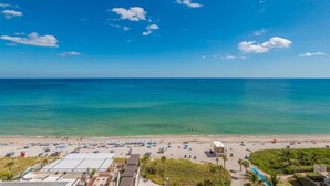 A beach with clear blue water, umbrellas, and people. - Relaxing Getaway with Intracoastal Views (Hollywood)