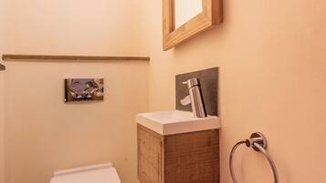 Ein kleines Badezimmer mit Toilette, Waschbecken, Spiegel und Handtuchhalter.