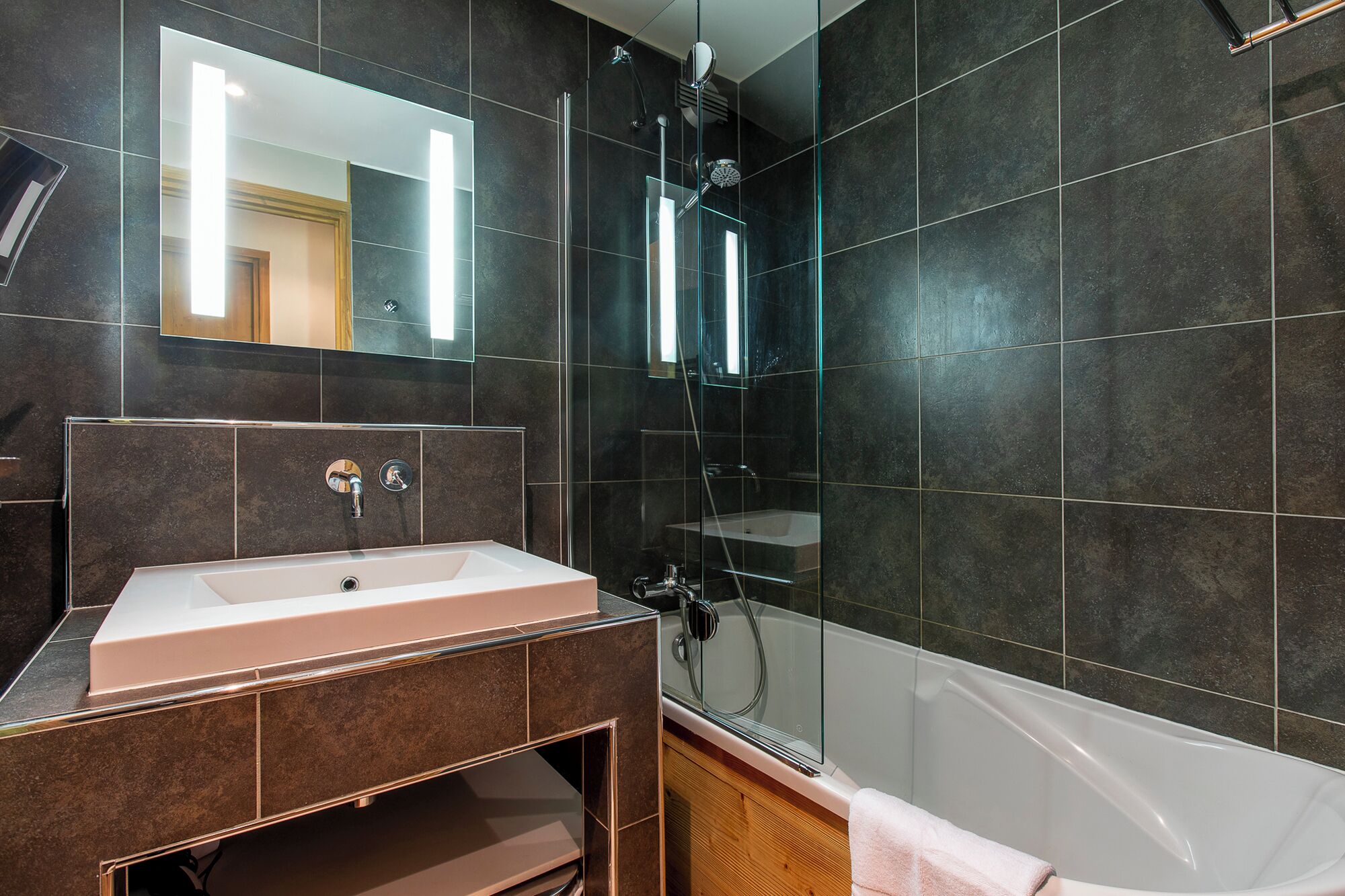 A modern bathroom with a large mirror, a sink, a shower, and a bathtub.