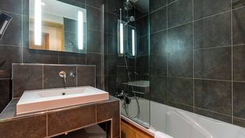 A modern bathroom with a large mirror, a sink, a shower, and a bathtub.