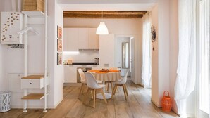 A modern kitchen with white cabinets, a wooden countertop, and a hanging pendant light.