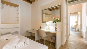 A hotel room with a bed, a desk, a chair, a mirror, and a bathroom visible through an open door. - Opera House (Verona)