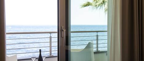 A balcony with a table, a chair, and a bottle of wine.