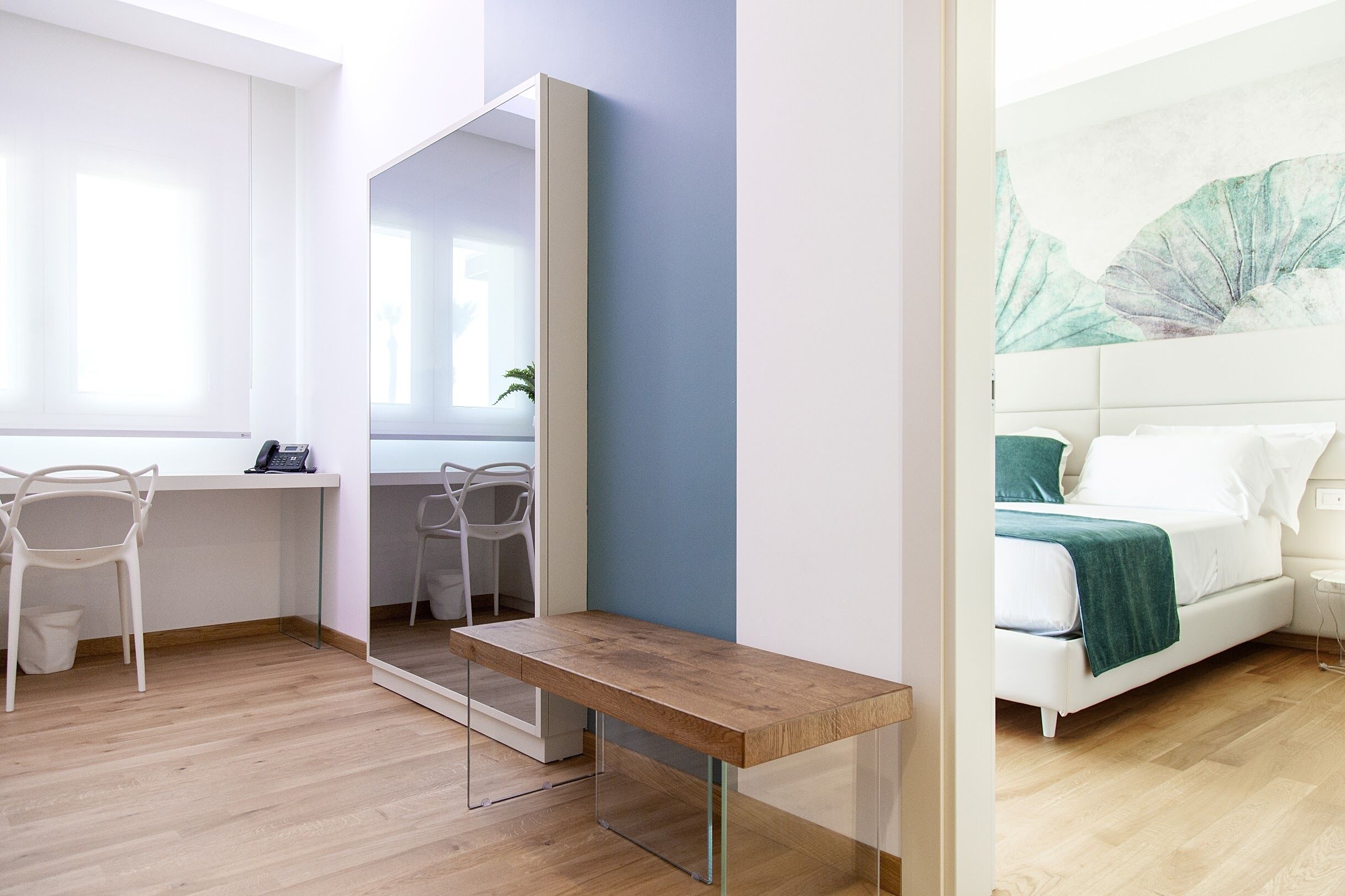 Een moderne slaapkamer met een bed, nachtkastje en een grote spiegel.