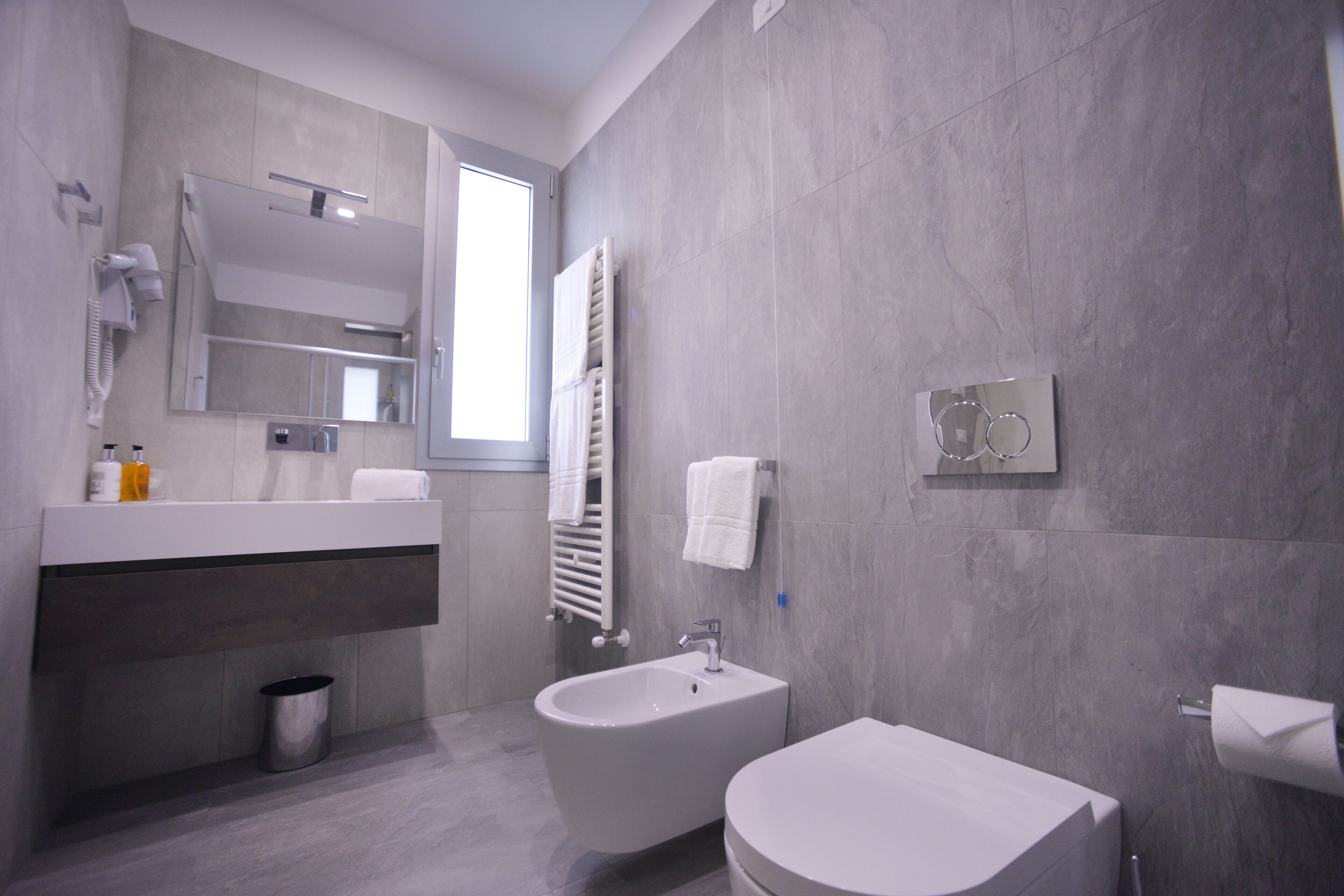 Een moderne badkamer met een toiletbril, wastafel, spiegel en handdoekhouder.