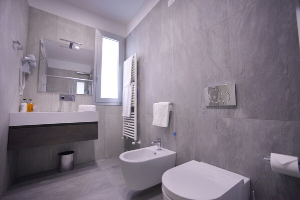 A modern bathroom with a bidet, a sink, a mirror, and a towel rack. - Santantonioresort (Riposto)
