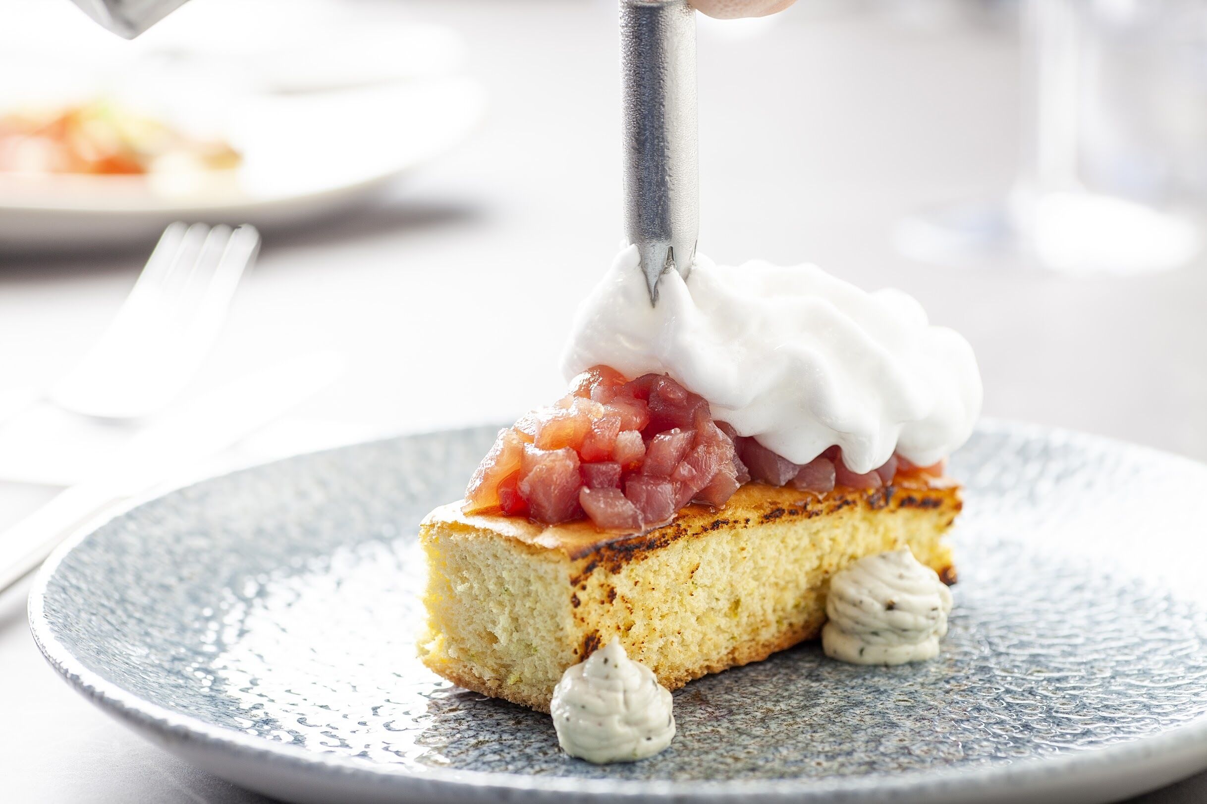 A slice of cake with whipped cream and diced fruit on a plate.