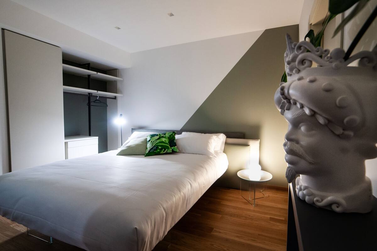 Une chambre moderne avec un grand lit, une armoire intégrée et un buste décoratif.
