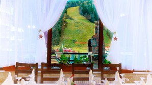 A restaurant with a view of a green hillside and a brick chimney.