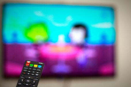 Un control remoto frente a una pantalla de televisión desenfocada.