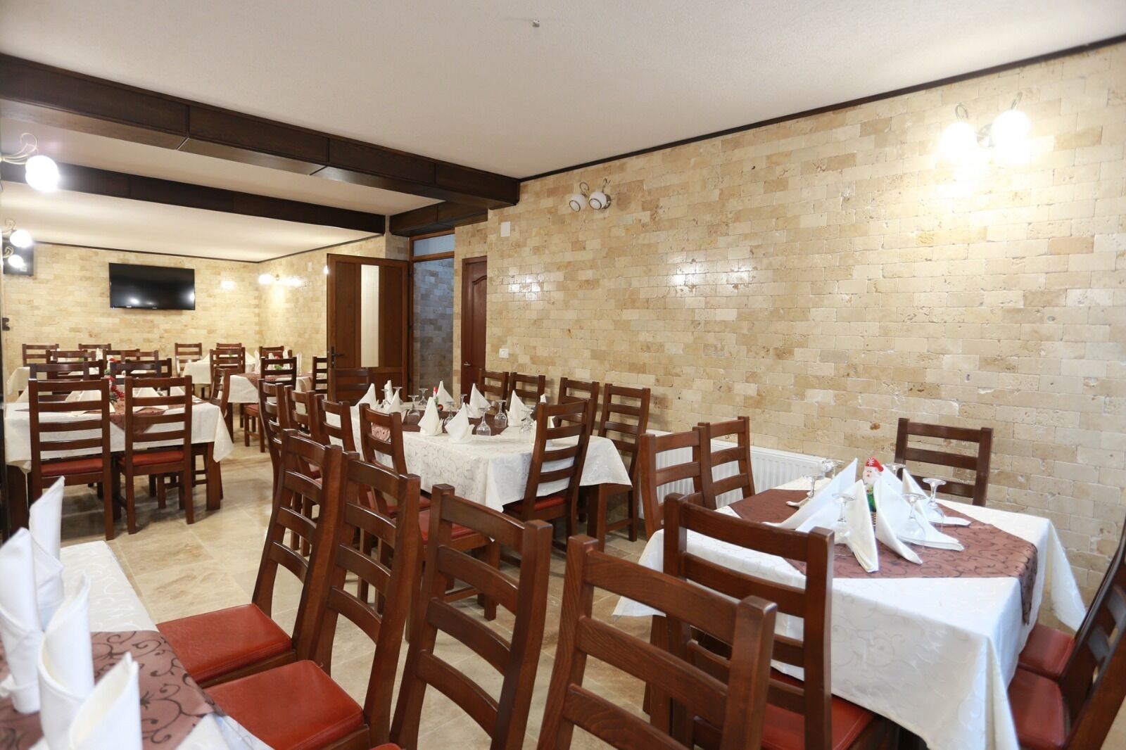 Un restaurante con varias mesas y sillas, cada conjunto con manteles y servilletas blancos.