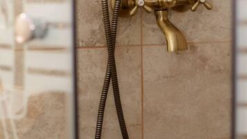 Un cabezal de ducha de bronce con manguera flexible y un rociador de mano.