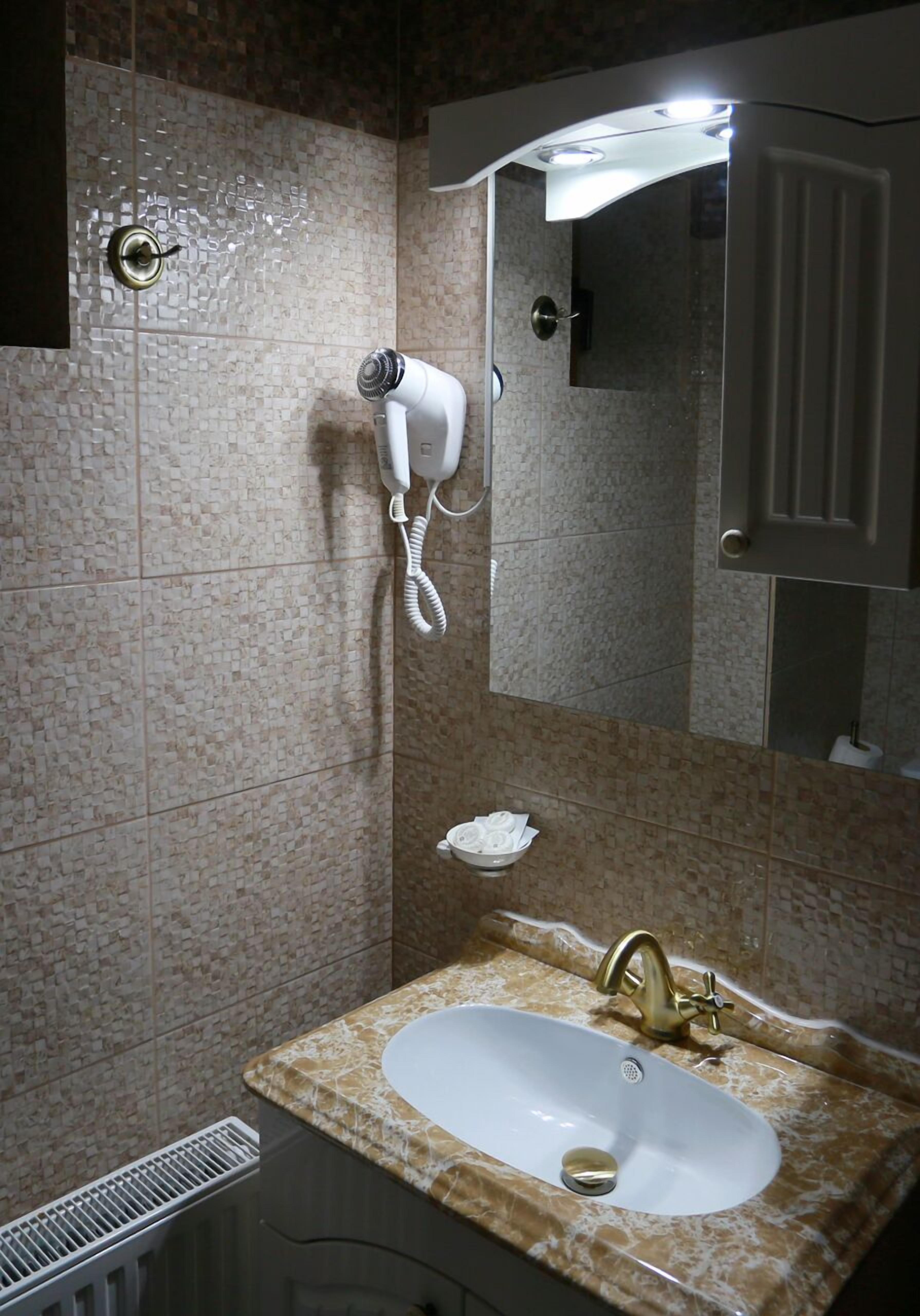 Un baño con lavamanos, espejo y toallero.
